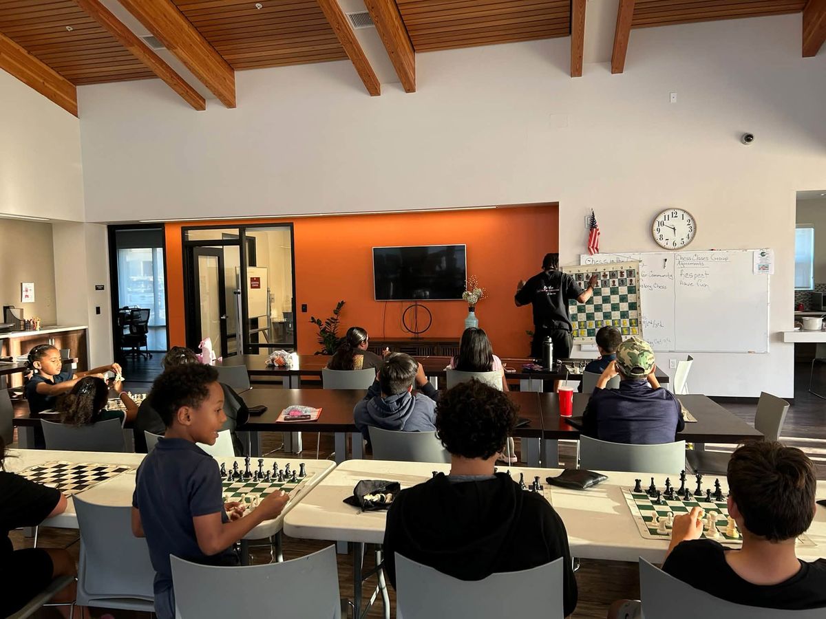 Children playing chess at tables in the Paradise Creek community room.