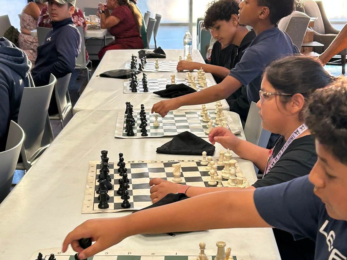 Players lined up along a table of chess boards during a Chess at the Creek class.