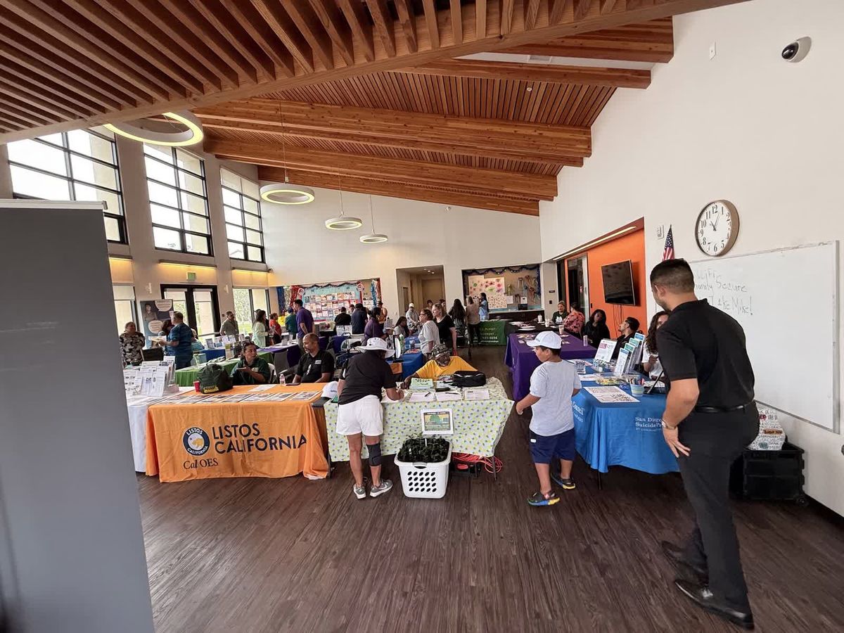 A community hall lined with service-provider tables during the Paradise Creek Summer Extravaganza.